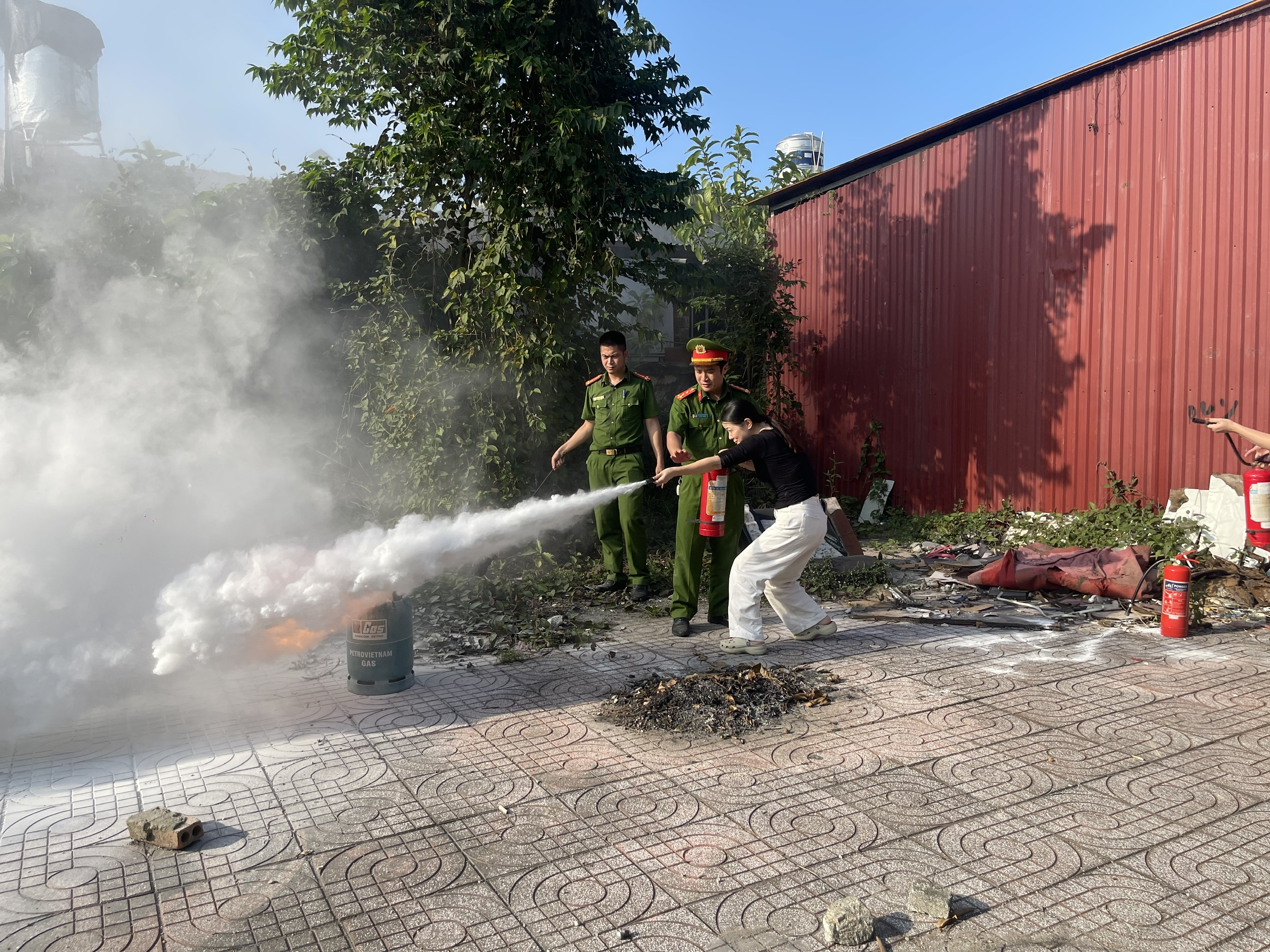 A group of people standing next to a fire extinguisherDescription automatically generated